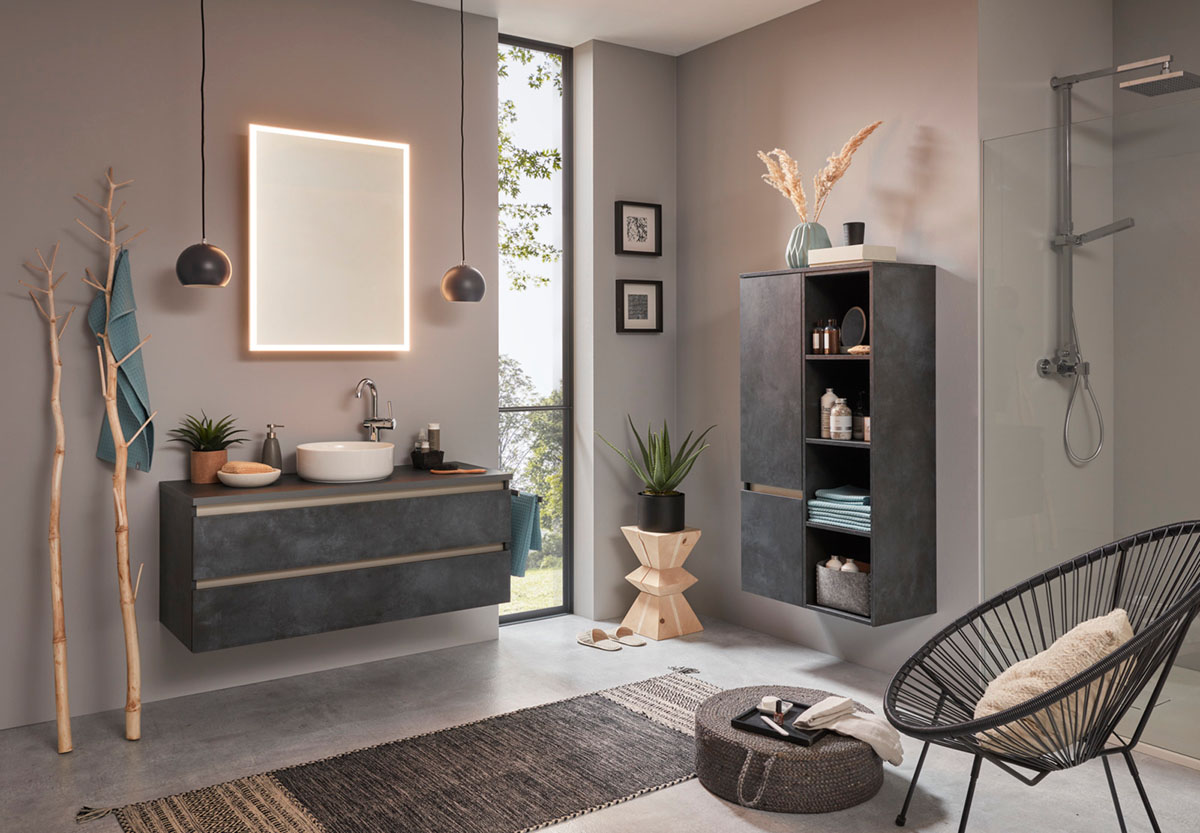 Netjes afgewerkte badkamer, donkergrijze greeploze meubels, warme verlichting. In de hoek een regendouche met afneembare handkop.
