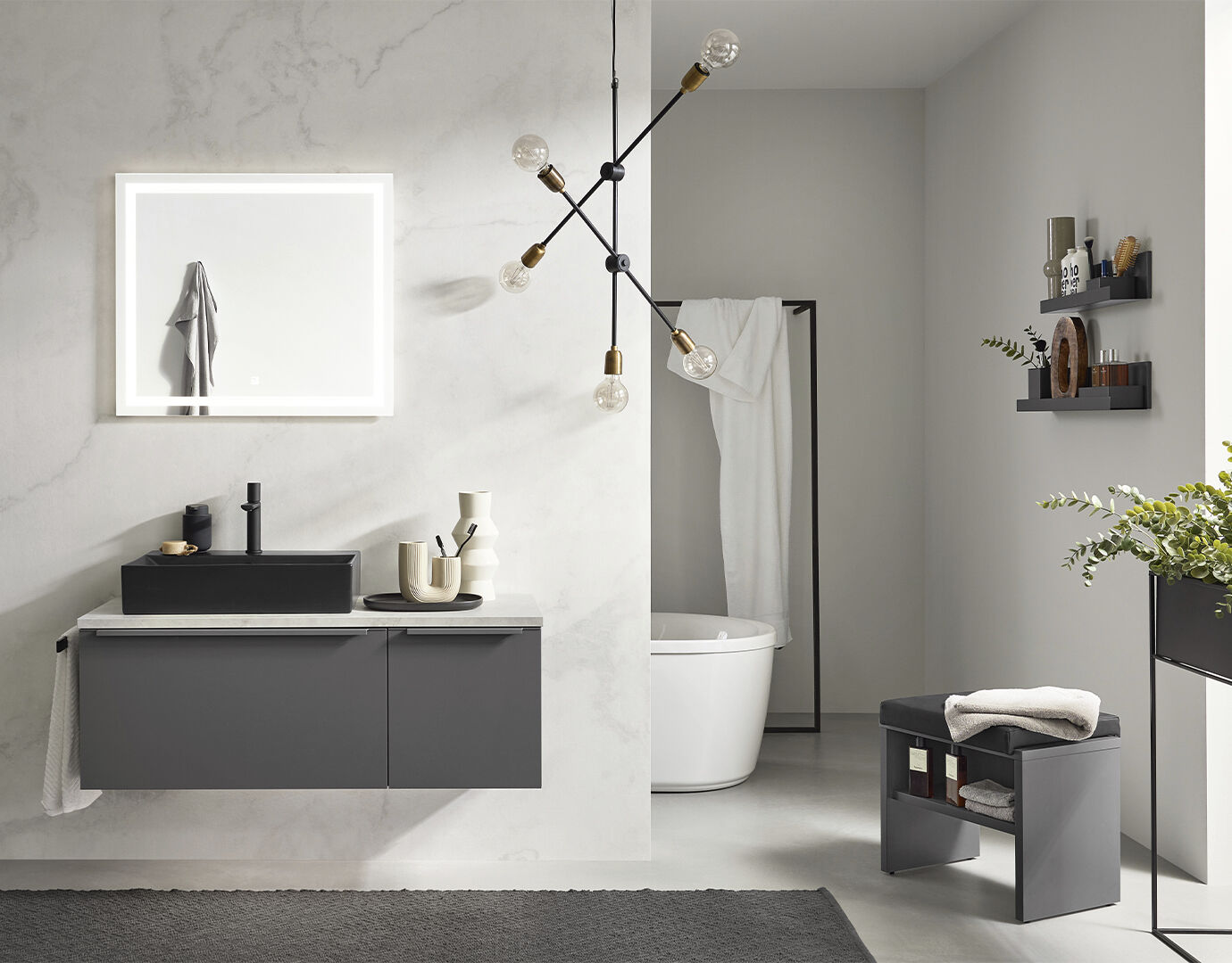 Badkamer met hangend wasmeubel, design lamp aan het plafond, op de achtergrond een vrijstaand bad. De muur heeft een marmer look.