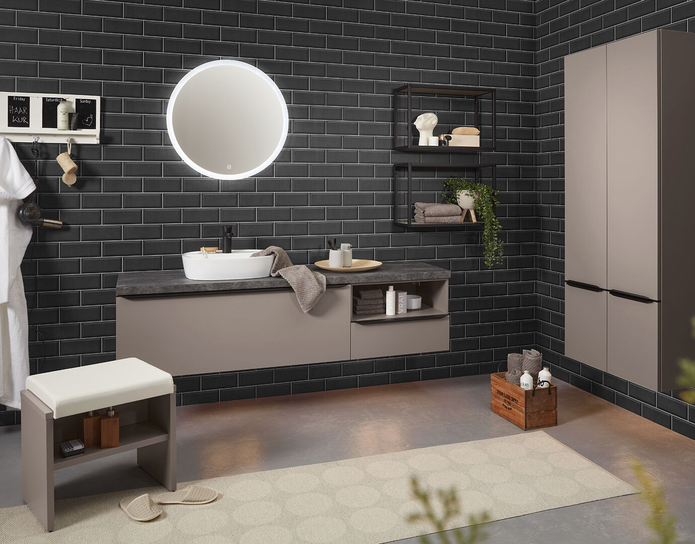 Badkamer met metro tegels aan de muur, grijsroze meubels en een ronde spiegel met randverlichting